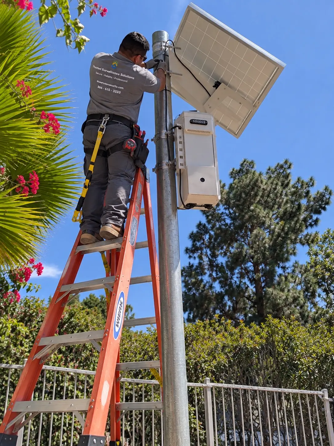 Three Factor Security technician installing a solar panel and equipment enclosure for a construction-site monitoring system with battery backup.
